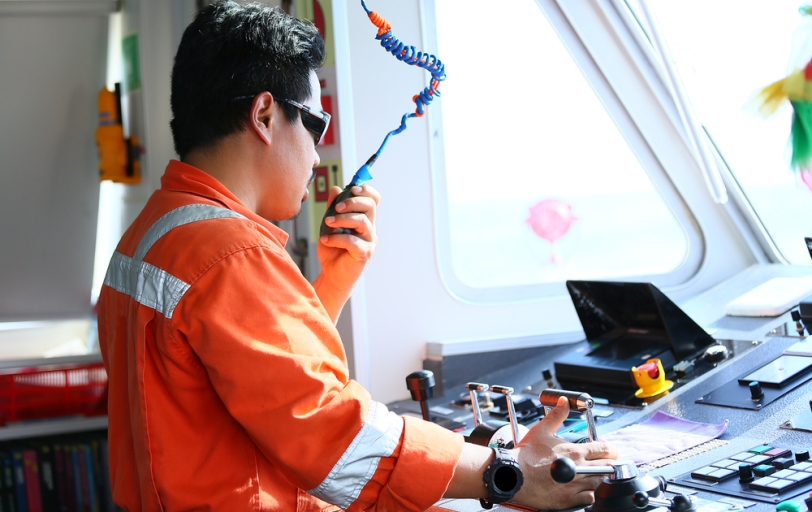 Schiffsingenieur kommuniziert im Maschinenraum mit Funkgerät.