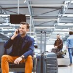 Reisender telefoniert im Flughafen mit Gepäck.