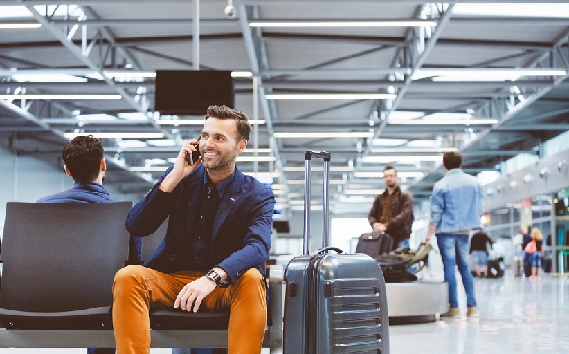 Reisender telefoniert im Flughafen mit Gepäck.