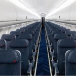 Leere Flugzeugkabine mit blauen Sitzen und Mittelgang.