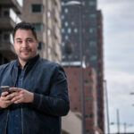 Mann in Stadt hält Smartphone in der Hand