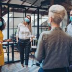 Besprechung im Büro mit Masken während Pandemie.