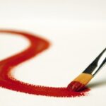 Pinsel malt rote Linie auf weißem Papier.