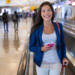 Lächelnde Frau mit Handy im Flughafen-Terminal