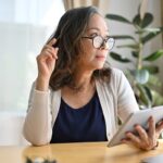 Frau mit Tablet, nachdenklich am Schreibtisch.