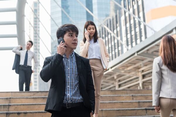 Joven ejecutivo en primer plano bajando las escaleras y hablando por celular.