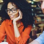 Mujer y hombre, ambos con lentes, en una reunión informal.