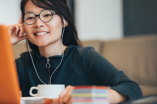 Persona sonriente con auriculares junto a una taza.