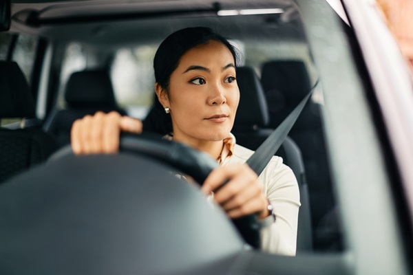 Woman driving car attentively.