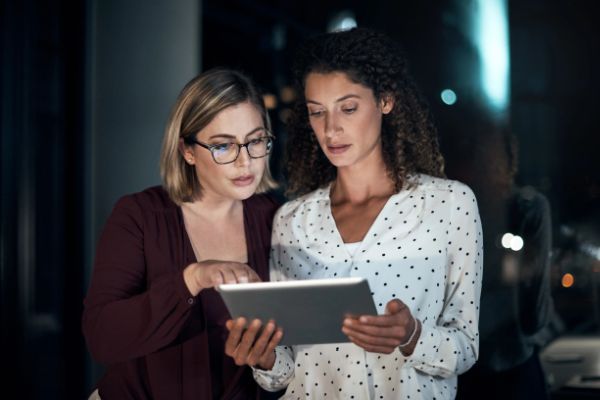 Dos mujeres ejecutivas revisan información en una tableta digital.