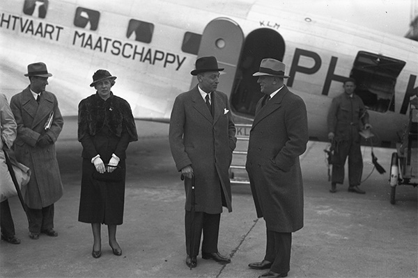 Personas conversando frente a un avión antiguo KLM.