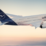 Un avión Airbus A380 de Lufthansa, de color blanco y azul oscuro en la cola y en el alerón trasero, surca el cielo durante la tarde.