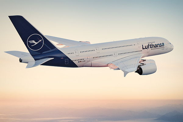 Un avión Airbus A380 de Lufthansa, de color blanco y azul oscuro en la cola y en el alerón trasero, surca el cielo durante la tarde.