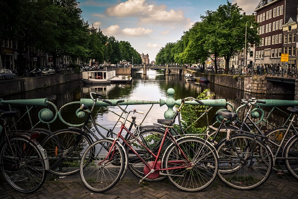 Varias bicicletas antiguas aparecen recostadas contra la baranda de un puente en un río de una ciudad europea.