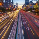 En una autopista de varios carriles, en una ciudad asiática, se ven haces de luces rojas, amarillas y blancas que indican el paso de autos a alta velocidad.