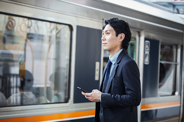 Businessman using smartphone near train.
