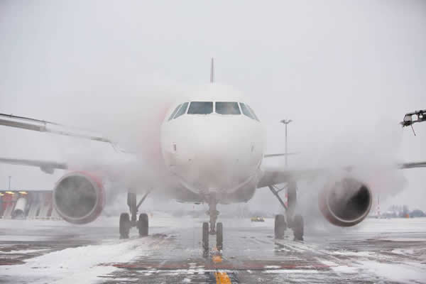 Un avión, visto de frente, avanza sobre una pista cubierta parcialmente de nieve.