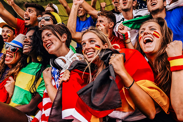 Cheering international sports fans in colorful attire.