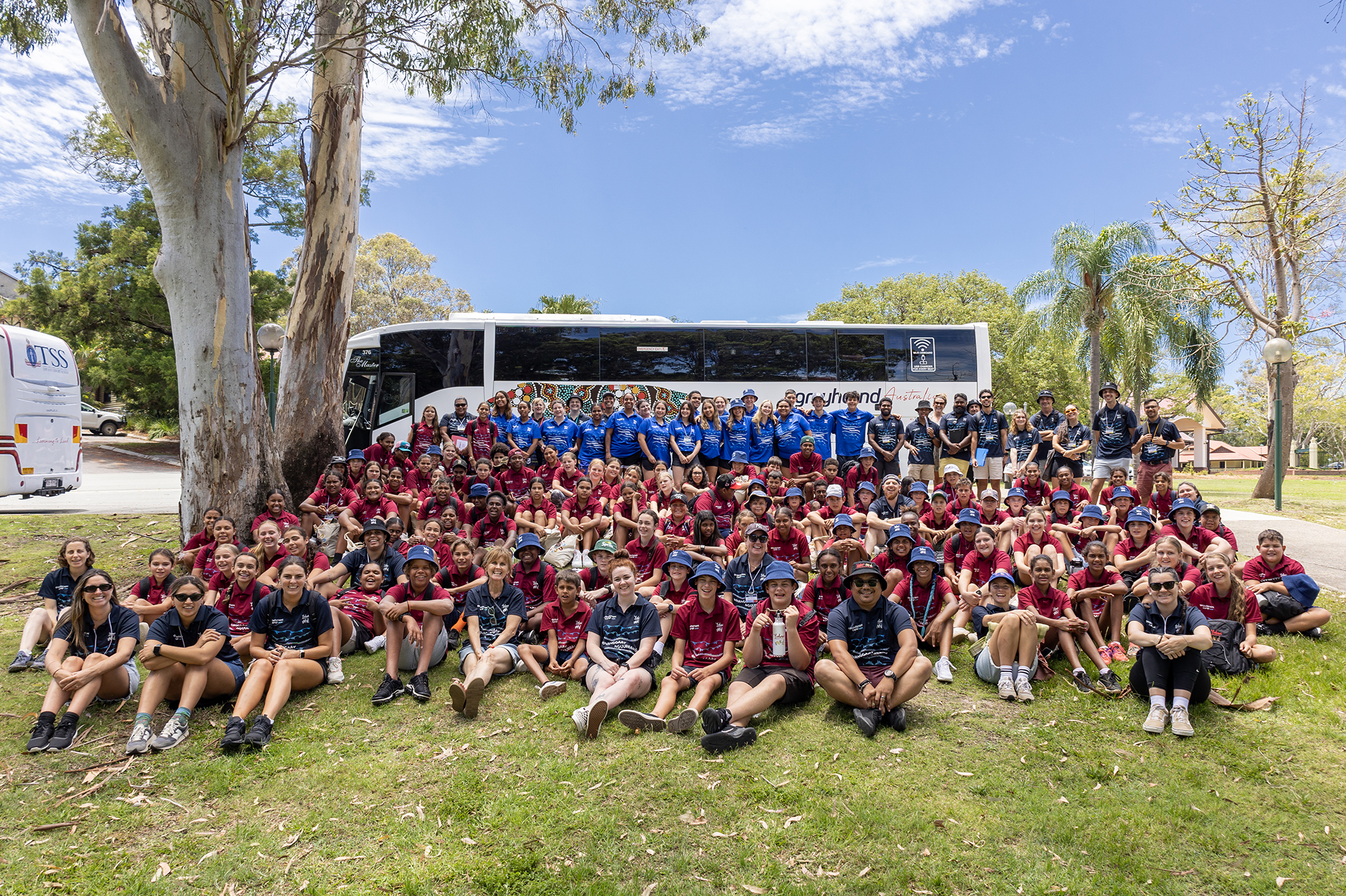 Más de un centenar de empleados de BCD están sentados sobre el césped, con un bus blanco en el fondo, en actividades de la iniciativa Making a Difference.