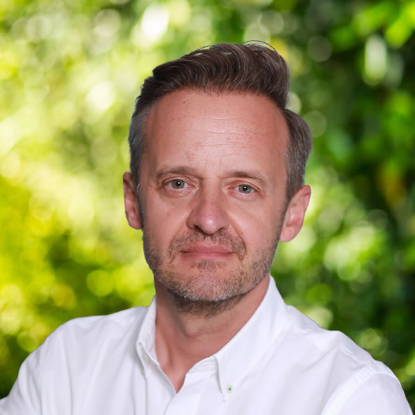 Adam-Kuna-image Homme posant devant fond vert flou.