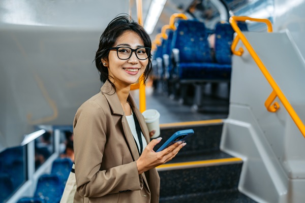 Femme souriante avec smartphone dans un bus moderne.