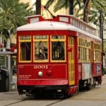 The image is a photograph of a streetcar in New Orleans. A streetcar is an electric vehicle that runs on rails in the streets of a town, also known as a tram in British English.