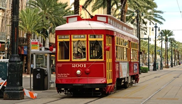 The image is a photograph of a streetcar in New Orleans. A streetcar is an electric vehicle that runs on rails in the streets of a town, also known as a tram in British English.