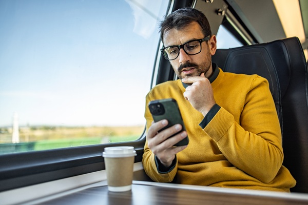 Man in yellow sweater using smartphone on train