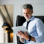 Uomo in ufficio sorride leggendo tablet.
