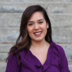 Donna sorridente con camicetta viola su scale