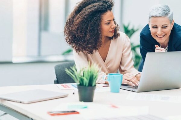 Donne professioniste in un ufficio guardano insieme lo schermo di un computer portatile