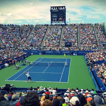 Tennis match on blue court before packed stadium crowd