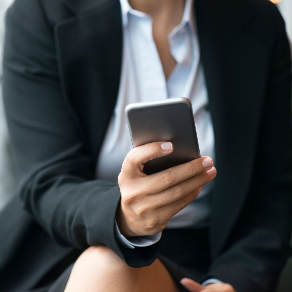 Businesswoman in black blazer holding a smartphone