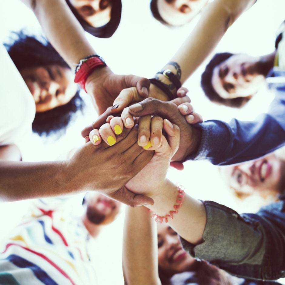 Diverse group stacking hands together in a circle