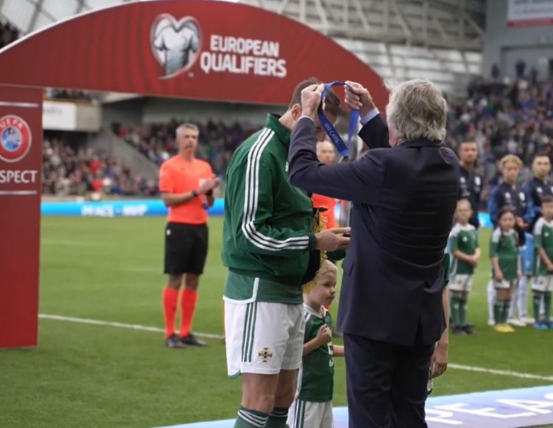 Official presents medal to Northern Ireland player before match