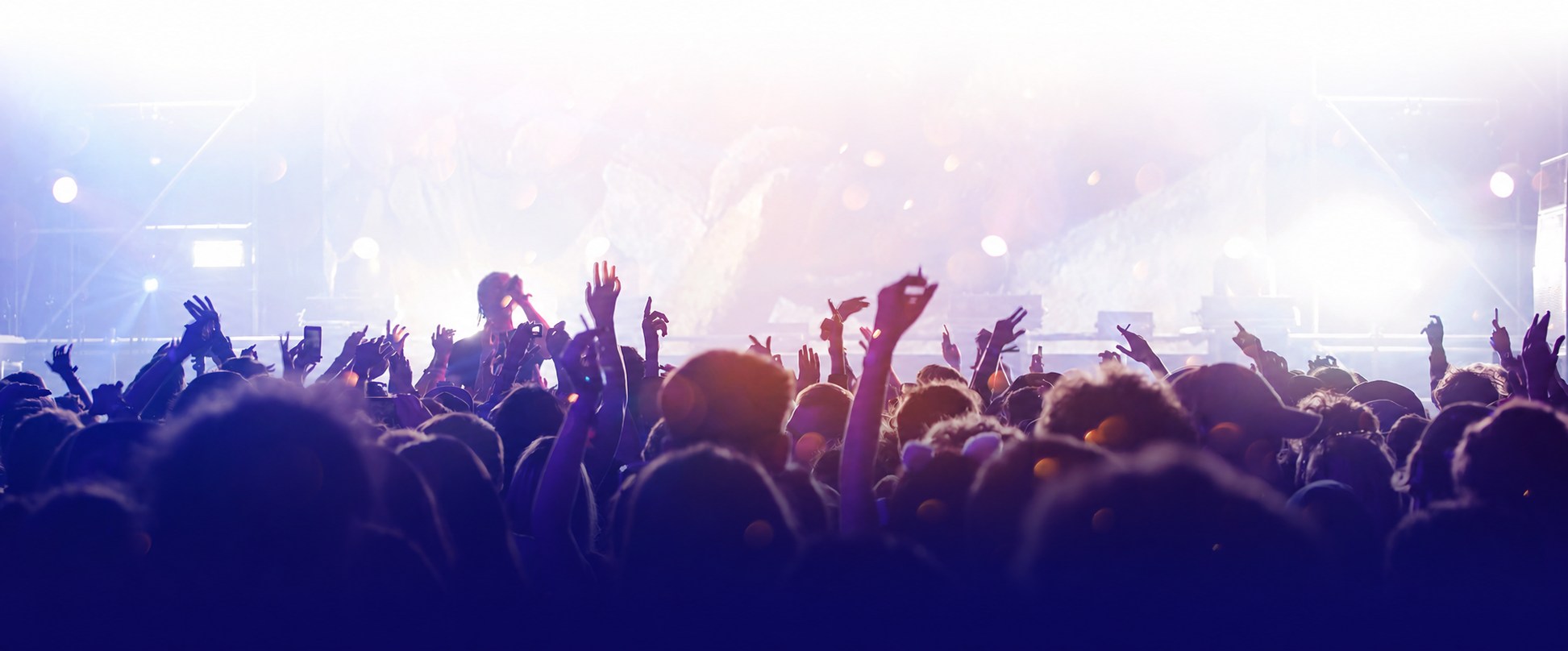 Crowd raises hands at brightly lit concert
