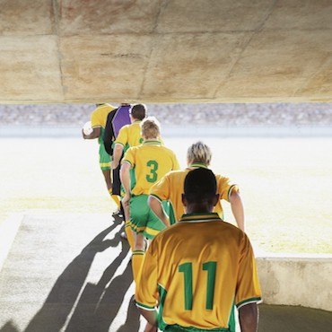Soccer players in yellow jerseys walk from tunnel