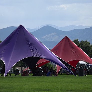 Purple and red canopy tents on a mountain lawn