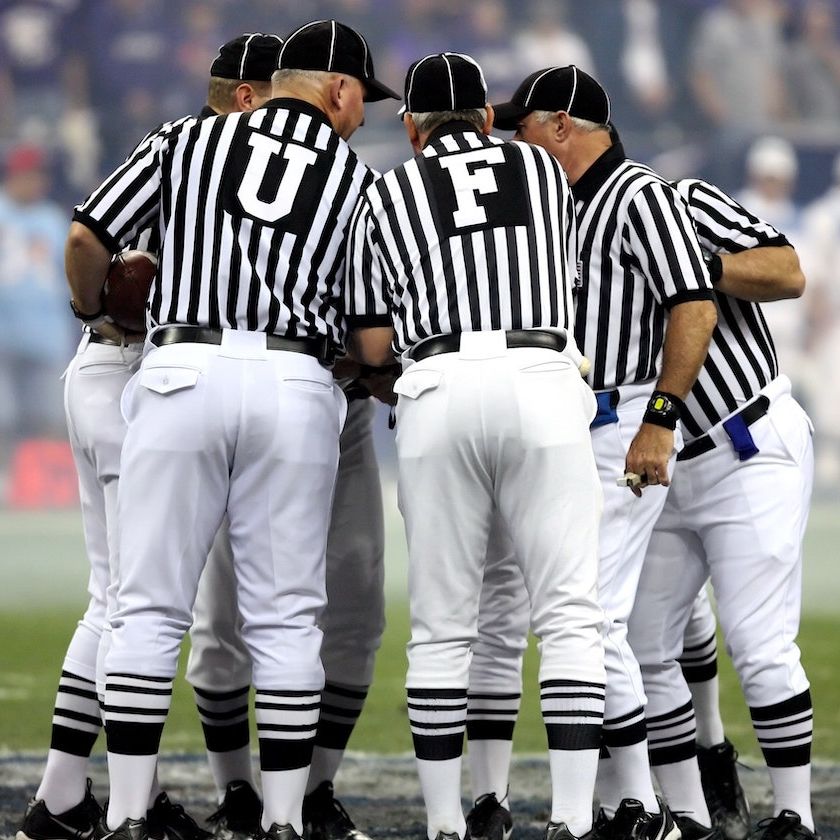 Football referees huddle on field before play