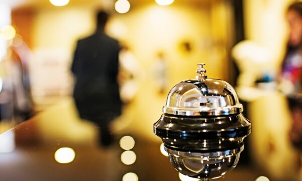 Hotelreceptie bel op toonbank, onscherp personeel.