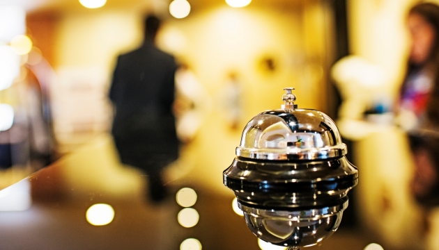 Hotelreceptie bel op toonbank, onscherp personeel.