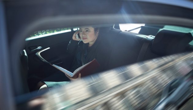Vrouw in auto met telefoon en boek