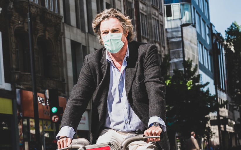 Man fietst door stad met mondmasker.