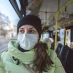 Vrouw met maskertje in bus, winterkleding, veiligheid