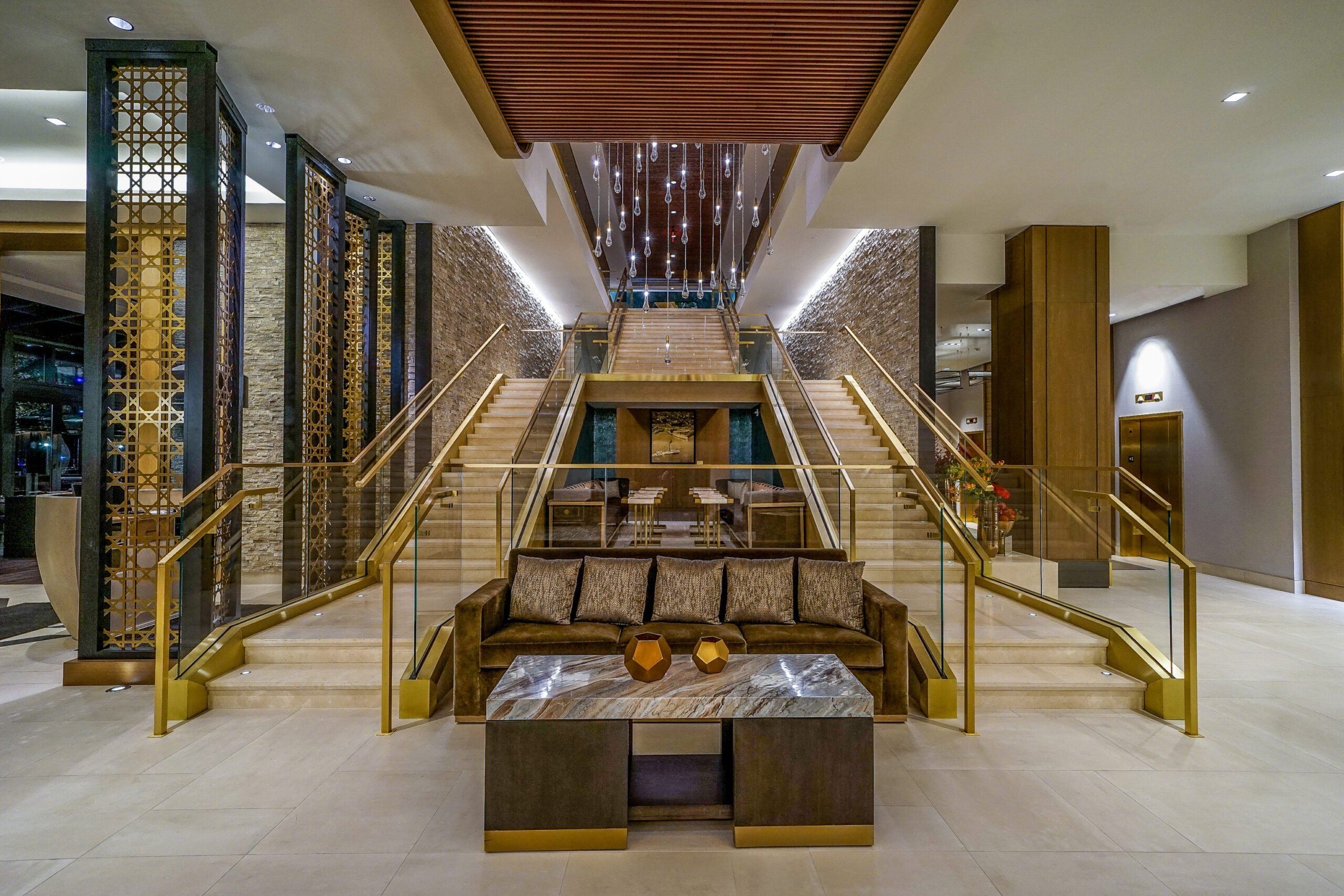 Luxe hotellobby met trap en moderne meubels.