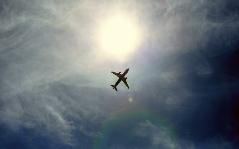 Vliegtuig vliegt voor de zon in heldere lucht.