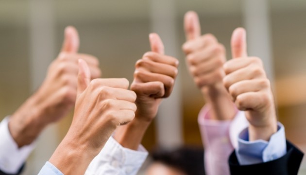 Groep mensen steekt duimen omhoog voor succes.