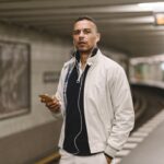 Man with headphones waiting on subway platform.