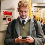 Man using smartphone on subway train.