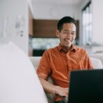 Smiling man using laptop at home
